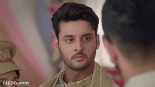 A Man With A Beard Is Standing In Front Of A Group Of People And Looking At Something . GIF