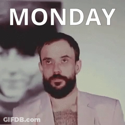 A Man With A Beard Is Standing In Front Of A Monday Poster GIF