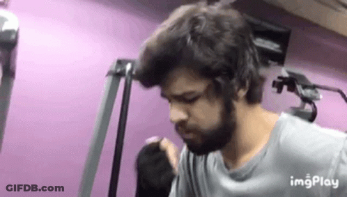 A Man With A Beard Is Standing In Front Of A Pink Wall In A Gym . GIF