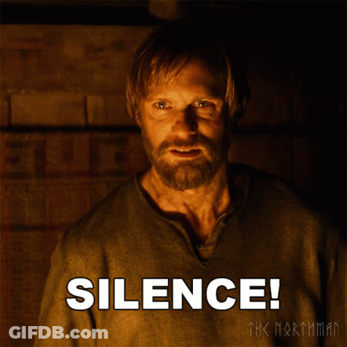 A Man With A Beard Is Standing In Front Of A Poster That Says Silence GIF