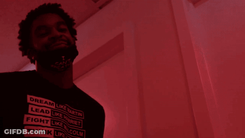 A Man With A Beard Is Standing In Front Of A Red Door GIF
