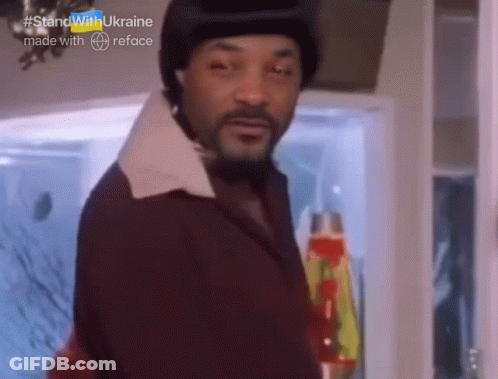 A Man With A Beard Is Standing In Front Of A Refrigerator With #Standwithukraine Made With Reface Written On The Bottom GIF