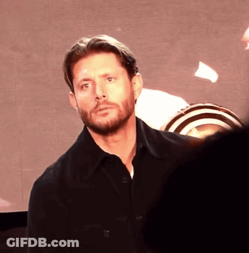 A Man With A Beard Is Standing In Front Of A Screen GIF