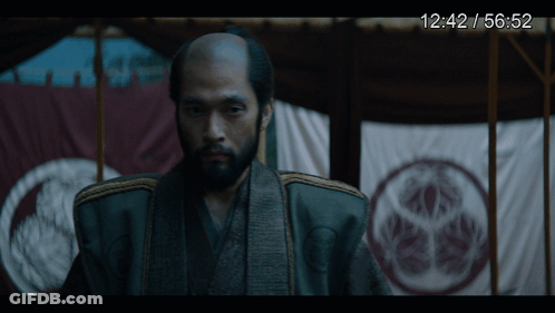 A Man With A Beard Is Standing In Front Of A Screen That Says 12:42 / 56.52 GIF