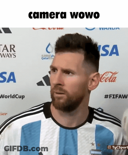 A Man With A Beard Is Standing In Front Of A Sign That Says Camera Owo GIF
