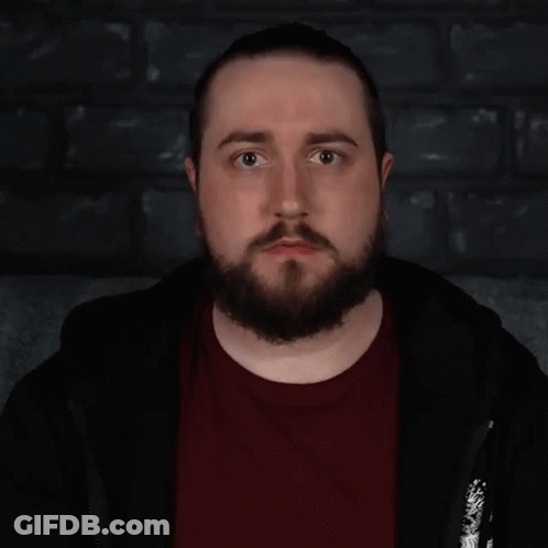 A Man With A Beard Is Standing In Front Of A Sign That Says " Lovely " GIF