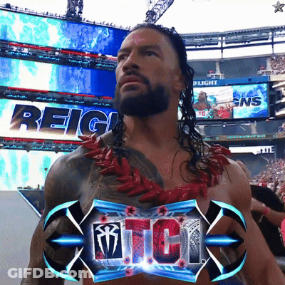 A Man With A Beard Is Standing In Front Of A Sign That Says Reigns GIF