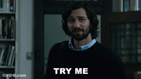 A Man With A Beard Is Standing In Front Of A Sign That Says " Try Me " GIF