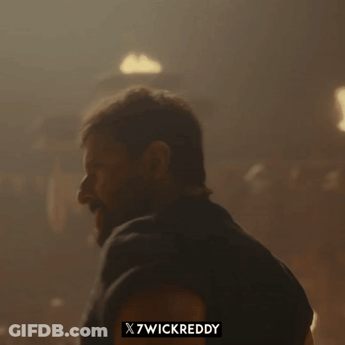A Man With A Beard Is Standing In Front Of A Sign That Says X7wickreddy On It GIF