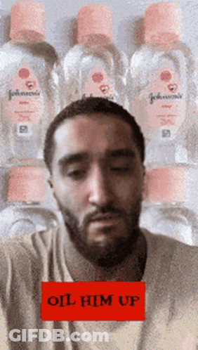 A Man With A Beard Is Standing In Front Of A Stack Of Johnson 'S Baby Oil GIF