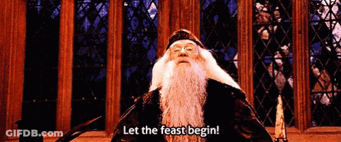 A Man With A Beard Is Standing In Front Of A Stained Glass Window And Says Let The Feast Begin . GIF