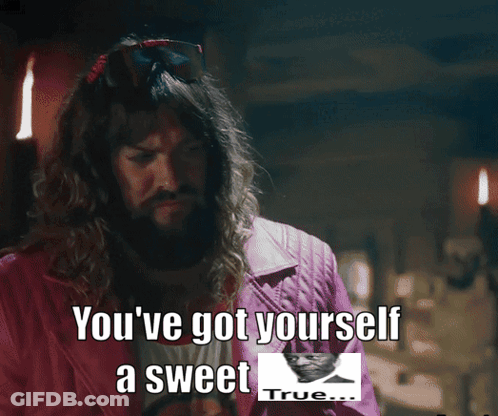 A Man With A Beard Is Standing In Front Of A Table With A Picture Of A Man And The Words " True " GIF