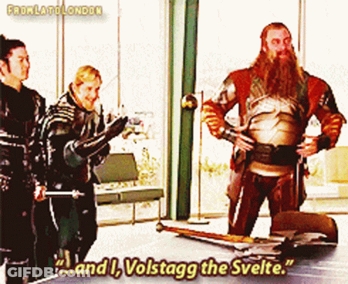 A Man With A Beard Is Standing In Front Of A Table With The Words " And I Volstagg The Svelte " GIF
