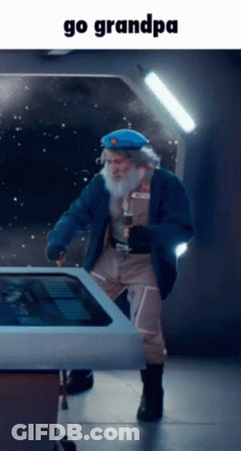 A Man With A Beard Is Standing In Front Of A Touchscreen With The Words Go Grandpa Below Him GIF
