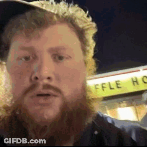 A Man With A Beard Is Standing In Front Of A Waffle House GIF