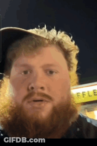 A Man With A Beard Is Standing In Front Of A Waffle Restaurant GIF