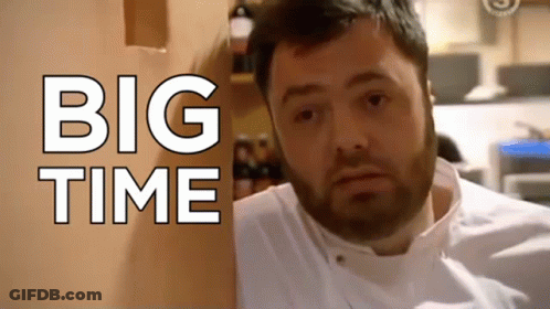 A Man With A Beard Is Standing In Front Of A Wall That Says Big Time GIF