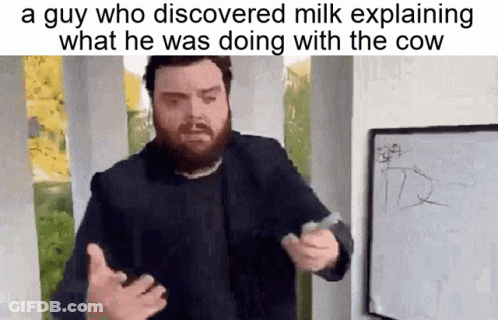 A Man With A Beard Is Standing In Front Of A Whiteboard Explaining What He Was Doing With The Cow . GIF