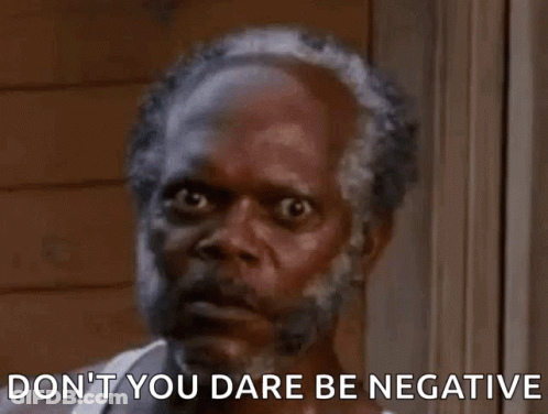A Man With A Beard Is Standing In Front Of A Window With The Words `` Don 'T You Dare Be Negative '' . GIF