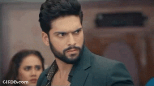 A Man With A Beard Is Standing In Front Of A Woman In A Room . GIF