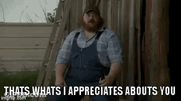 A Man With A Beard Is Standing In Front Of A Wooden Fence . GIF