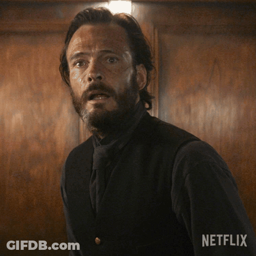 A Man With A Beard Is Standing In Front Of A Wooden Wall With Netflix Written On The Bottom Right GIF