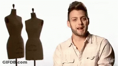 A Man With A Beard Is Standing In Front Of Three Mannequins GIF