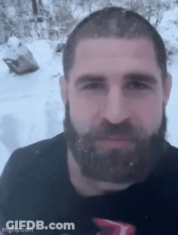 A Man With A Beard Is Standing In The Snow GIF