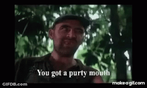 A Man With A Beard Is Standing In The Woods And Talking To Someone . GIF