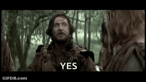 A Man With A Beard Is Standing In The Woods Talking To A Group Of People . GIF