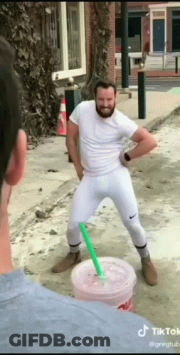 A Man With A Beard Is Standing Next To A Cup Of Drink With A Straw . GIF