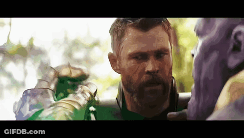 A Man With A Beard Is Standing Next To A Purple And Green Character . GIF