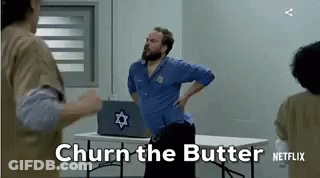A Man With A Beard Is Standing Next To A Table With A Laptop On It . GIF