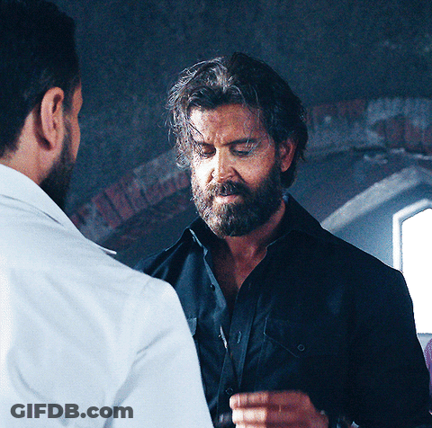 A Man With A Beard Is Standing Next To Another Man GIF