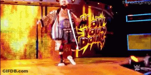 A Man With A Beard Is Standing On A Stage In Front Of A Wall That Says Low Your Doin 'S GIF