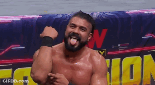 A Man With A Beard Is Sticking His Tongue Out In Front Of A Sign That Says Wrestling . GIF
