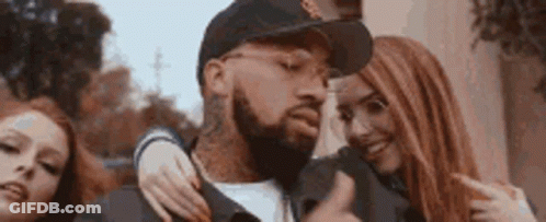 A Man With A Beard Is Surrounded By Two Women . GIF