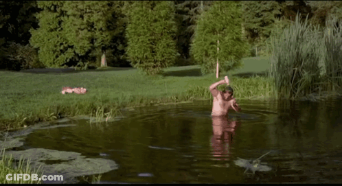 A Man With A Beard Is Swimming In A Pond . GIF