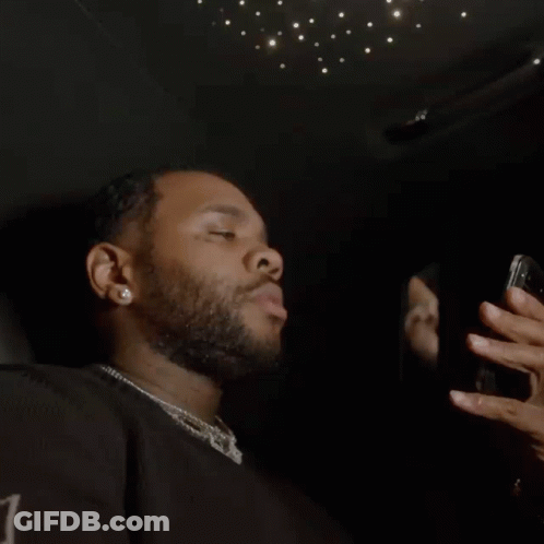 A Man With A Beard Is Taking A Picture Of Himself In A Mirror With His Cell Phone . GIF