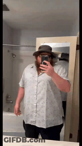 A Man With A Beard Is Taking A Selfie In Front Of A Mirror GIF
