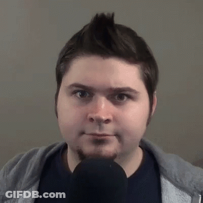 A Man With A Beard Is Talking Into A Microphone And Making A Funny Face . GIF