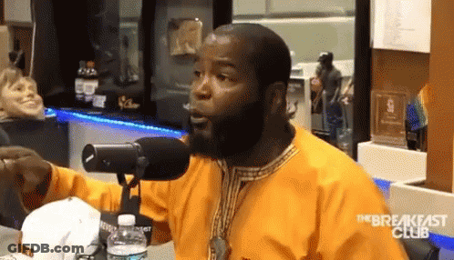 A Man With A Beard Is Talking Into A Microphone With The Breakfast Club Written On The Bottom GIF