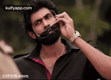 A Man With A Beard Is Talking On A Cell Phone While Wearing Sunglasses . GIF