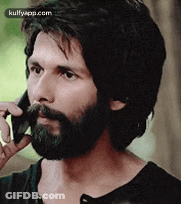 A Man With A Beard Is Talking On A Phone . GIF