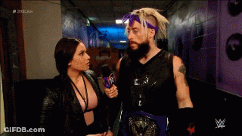 A Man With A Beard Is Talking To A Woman In A Hallway . GIF