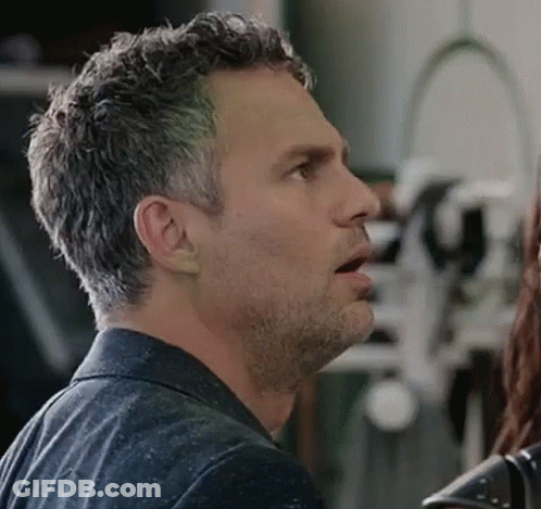 A Man With A Beard Is Talking To A Woman In A Room . GIF