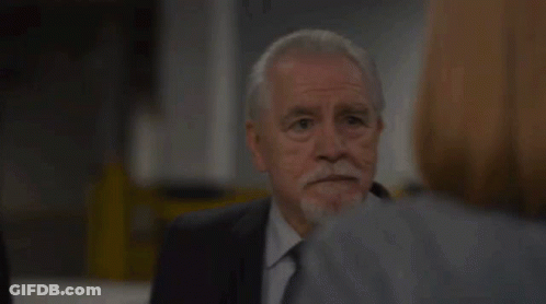 A Man With A Beard Is Talking To A Woman In A Suit And Tie . GIF