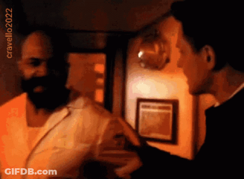A Man With A Beard Is Talking To Another Man In A Room With The Year 2022 On The Bottom Right GIF
