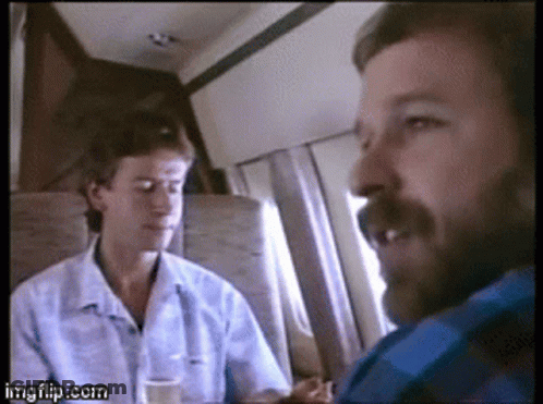 A Man With A Beard Is Talking To Another Man On A Plane . GIF
