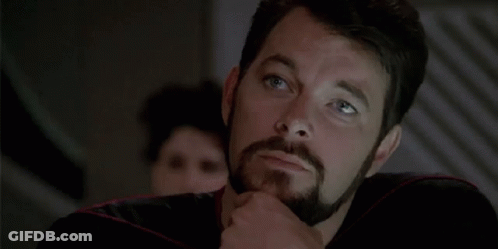 A Man With A Beard Is Thinking And Pointing To His Chin . GIF